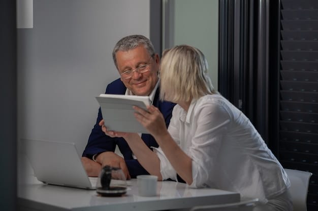 A health insurance broker sitting at a desk with a client, reviewing documents and using a tablet to compare different health insurance plans. They are both looking at the screen intently.