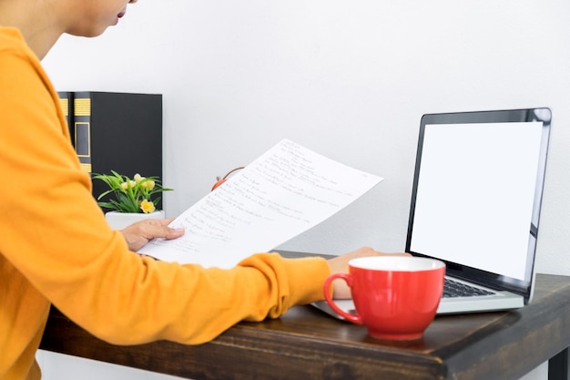 A person sitting at a desk, reviewing tax documents and a laptop displaying Form 8962. The image focuses on the meticulous process of reconciling tax credits during tax season, highlighting the importance of accuracy and attention to detail.