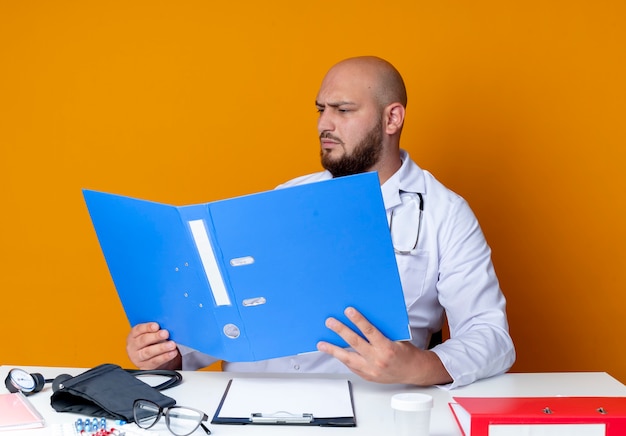 A person sitting at a desk reviewing various healthcare plan documents with a concerned expression. The layout focuses on multiple healthcare options laid out clearly.