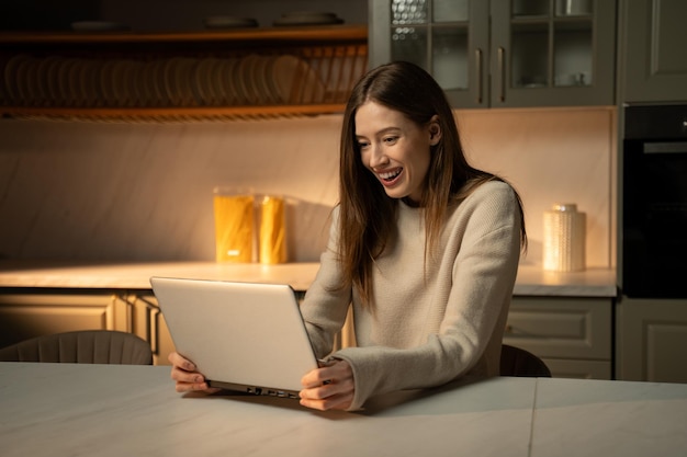 A smiling woman using a laptop, looking at a website displaying the ACA marketplace plans. The background shows a comfortable home setting.