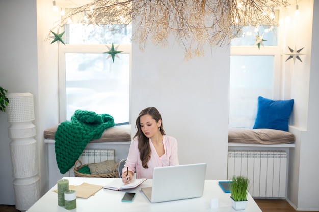 A person sitting at a desk, reviewing insurance paperwork with a pen in hand. The background is a cozy home office setup.