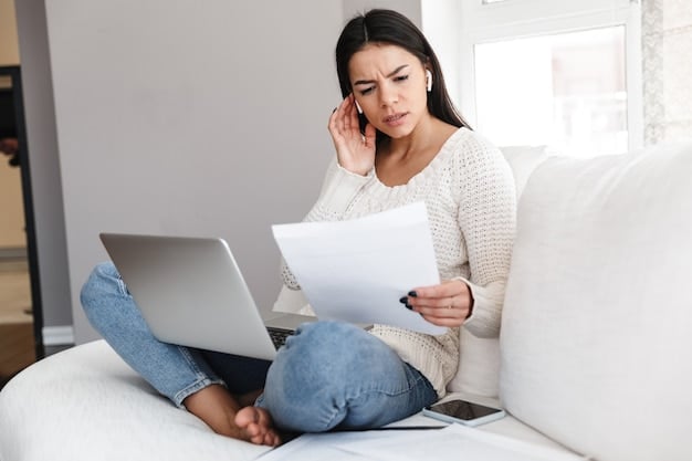 A person looking stressed and overwhelmed while reviewing medical bills on their laptop at home.