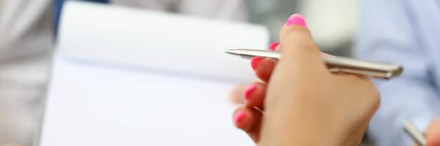 A close-up shot of a person's hands filling out an application form for health insurance, with a pen in hand. The background is blurred to focus on the act of applying.
