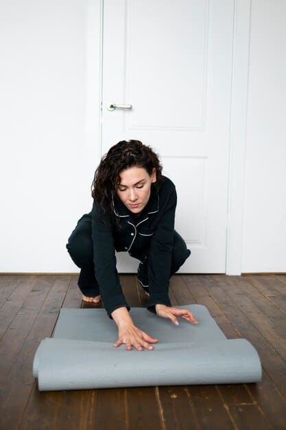 A person performing a modified child's pose on a yoga mat, illustrating proper alignment with props, in a softly lit studio.