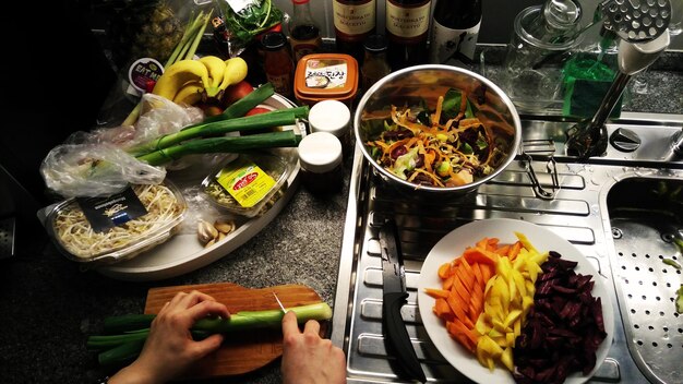 A bustling kitchen counter showcasing a variety of freshly cooked meal prep components in different stages of preparation: a bowl of cooked quinoa, neatly chopped bell peppers, grilled chicken breasts cooling on a rack, and a large pot of simmering lentil soup.