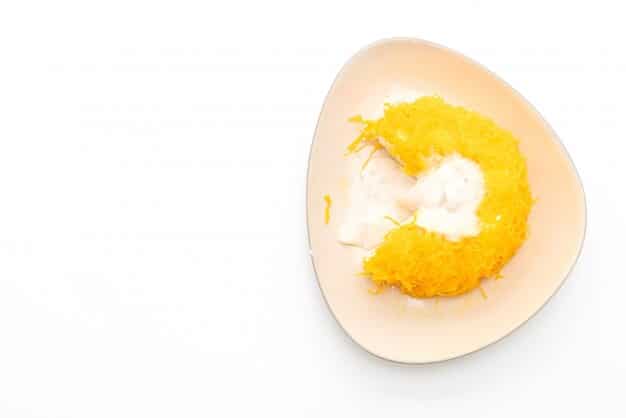 A close-up shot of a perfectly hard-boiled egg cut in half next to a small pile of golden-brown almonds on a clean white surface.