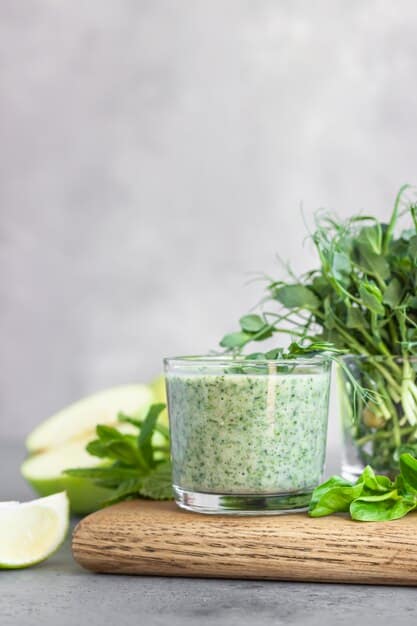 A close-up shot of a vibrant green smoothie in a clear glass, with a few visible spinach leaves and a background of fresh fruit implying healthy ingredients, natural light.