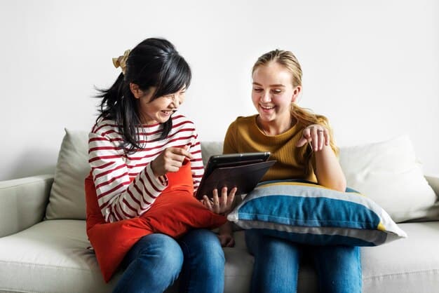 A caring parent and teenager sitting together on a couch, looking at a tablet screen, pointing and discussing, signifying open communication and shared digital space.