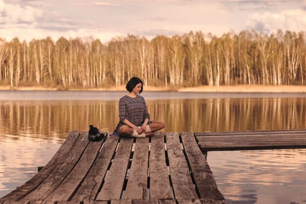 A person meditating calmly in a serene natural setting like a forest or by a tranquil lake, surrounded by soft, warm light.