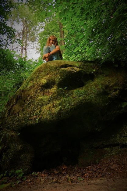 A person sitting peacefully on a moss-covered rock in a forest, eyes closed, with hands resting gently on their lap. The image should convey a sense of deep relaxation and connection with nature experienced during forest bathing. Highlight how this connection relates to Insider Knowledge: The Untapped Benefits of Forest Bathing for Mental Clarity and Focus.