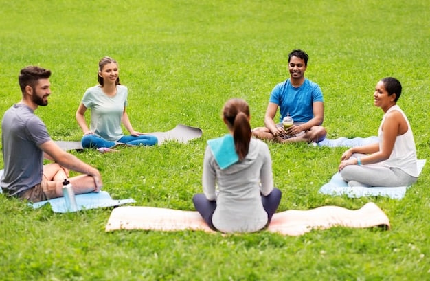 A group of people participating in a guided meditation session outdoors. They are sitting in a circle on yoga mats, with a serene forest backdrop. The instructor is leading them with a gentle voice, promoting relaxation and mindfulness.