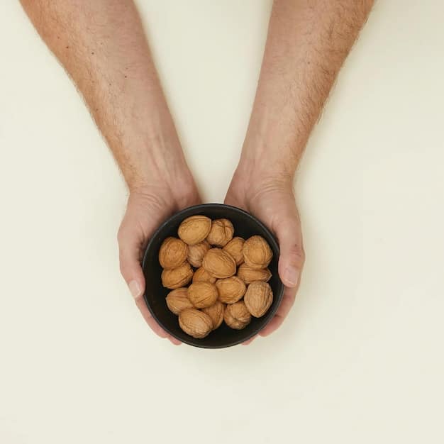 A close-up shot of a person's hand reaching for a bowl of mixed nuts and seeds, emphasizing the texture and natural colors of the snack. The background is blurred to focus attention on the healthy snack choice. The image relates to the importance of choosing nutrient-rich snacks in 
