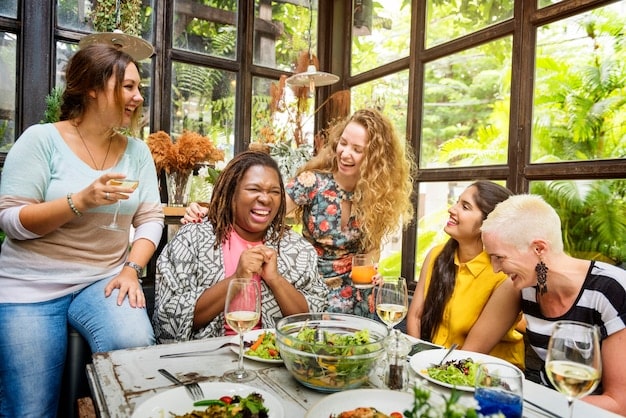 A group of friends laughing and enjoying a meal together outdoors, symbolizing the importance of social connections and support systems in maintaining well-being and avoiding burnout.